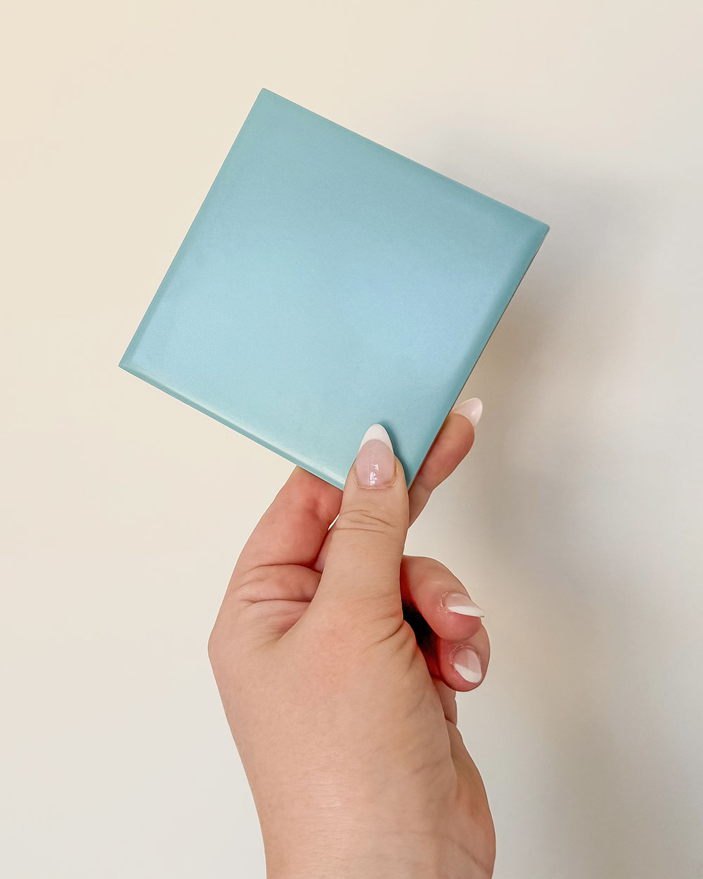 Hand holding a blue tile sample