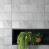 A vibrant shelf filled with plants, positioned in front of a stylish Solar Ash matt tiled wall.