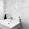 Clean and simple bathroom with a white sink and Solar White Matt Tiles covering the walls.