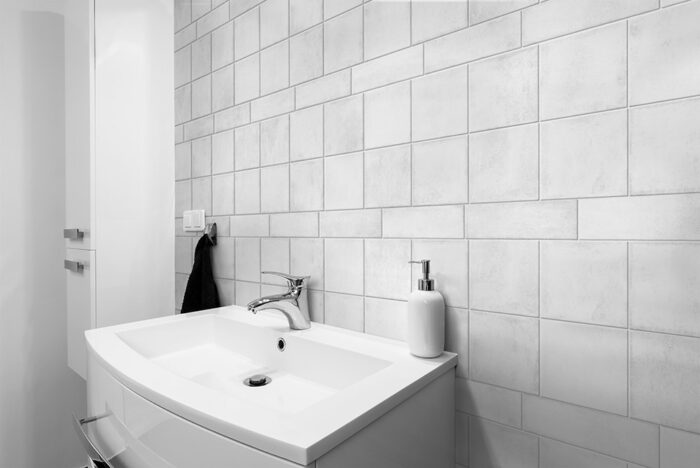 Clean and simple bathroom with a white sink and Solar White Matt Tiles covering the walls.